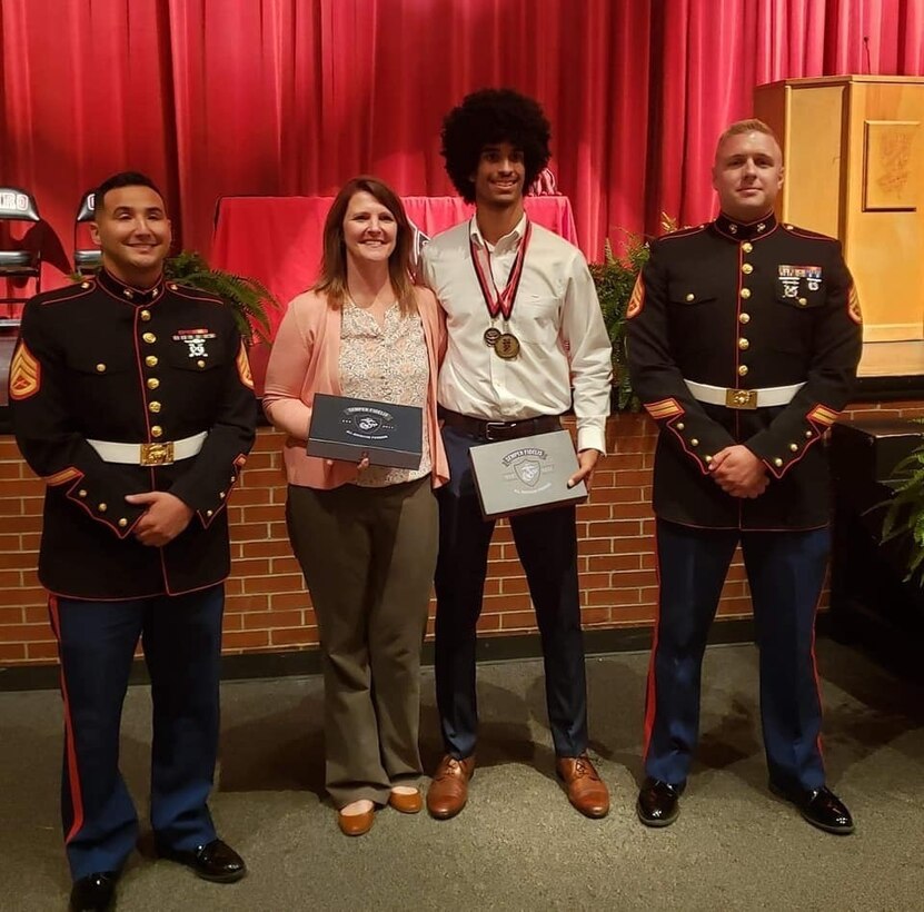 Staff Sgt. Michael Isaac and Staff Sgt. Michael Maynard, local Marine Corps recruiters, present a Battles Won Academy invitation to Robert P. Matthew, a Cairo High School student, during a visit to the high school, in Cairo, Georgia, April 24, 2019.  Matthew was one of 96 students across the country who the Marine Corps selected for the academy as part of the Semper Fidelis All-American Program. During the academy in Washington, D.C., students will participate in daily physical training with Marines, community service projects, listen to keynot speakers and more. (U.S. Marine Corps photo by Cpl. Mike Hernandez)