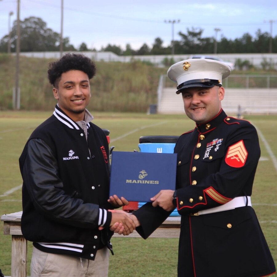 Kris Evans, a high school senior from Union Christian Academy and 2019 Semper Fidelis All-American, receives a Semper Fidelis All-American Program certificate of achievement from U.S. Marine Corps Sgt. Rodion Zabolotniy, a recruiter with Marine Corps Primary Contact Station Ruston, at the UCA Sports Complex in Farmerville, Louisiana, Oct. 11, 2019. Evans was selected not only for his athletic performance but for outstanding character, academic excellence, and community leadership that reflects the Marine Corps’ values of honor, courage, and commitment. Less than 100 students from across the nation attended the academy this past summer in Washington, D.C. (U.S. Marine Corps photo by Sgt. Shellie Hall)