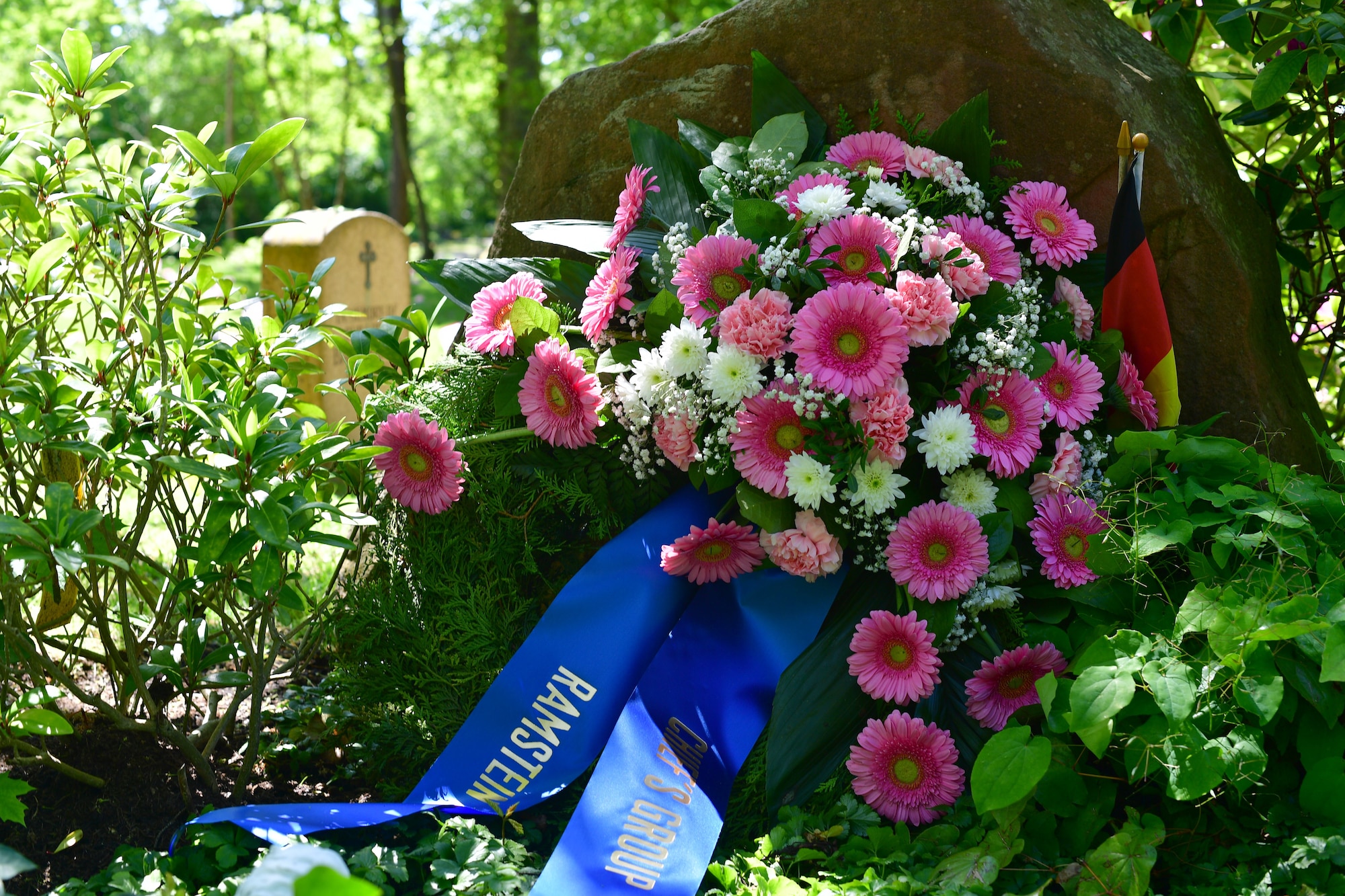 A floral wreath sits in front of a grave site.