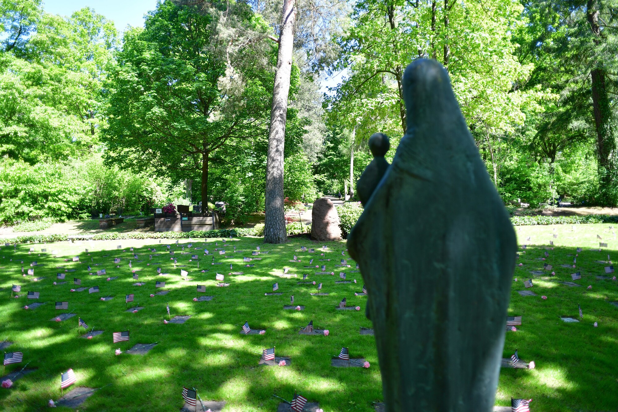 A grave site with a statue of Mary and baby Jesus in the foreground.