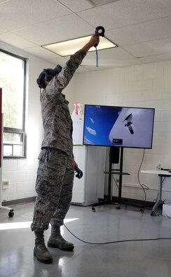 Airman 1st Class Emanual Oceguera 461st Aircraft Maintenance Squadron aircraft maintainer, reaches for a virtual part on the E-8C Joint Surveillance Target Attack Radar System aircraft at Robins Air Force Base, Georgia April 13, 2020. Virtual reality was brought to Team JSTARS to assist training maintainers remotely in a controlled environment.