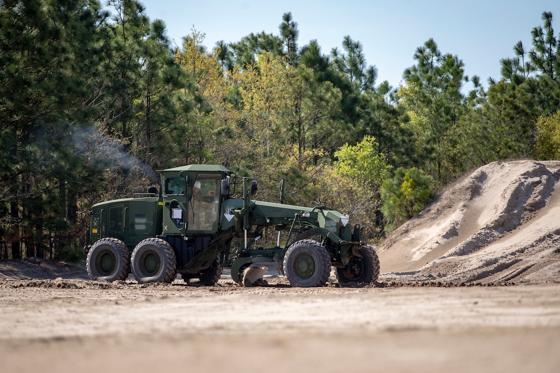 Lance Cpl. Oliver Cravens, a heavy equipment operator with Special Purpose Marine Air-Ground Task Force - Southern Command, grades a roadway during a command post exercise at Marine Corps Base Camp Lejeune, North Carolina, April 8, 2020. The road had suffered from the use of heavy machinery and was in need of repair. The Marines and Sailors of SPMAGTF-SC use the training opportunity of the CPX to both show their capabilities in a controlled environment and prepare for the upcoming mission. SPMAGTF-SC is poised to conduct crisis response, theater security cooperation, and general engineering training alongside partner nation militaries in Latin America and the Caribbean. Cravens is a native of Portland, Oregon. (U.S. Marine Corps photo by Cpl. Benjamin D. Larsen)