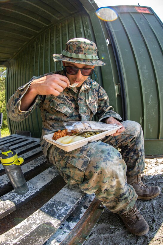 Lance Cpl. Daniel Bordenave, a water support technician with Special Purpose Marine Air-Ground Task Force - Southern Command, eats a hot meal that was made with the water he purified during the command post exercise at Camp Lejeune, North Carolina, April 8, 2020. Water support technician Marines used lightweight water purification systems to purify water before providing it to the combat engineer Marines working at another site. The CPX increases readiness and challenges SPMAGTF-SC command and control, communications and timely decision-making capabilities through simulated real-world scenarios. SPMAGTF-SC will be deployed into the Southern Command area of operation to provide crisis response preparedness efforts, security cooperation training and engineering events to help strengthen relations with partner nations throughout Central and South America. Bordenave is a native of Pleasanton, California. (U.S. Marine Corps photo by Sgt. Andy O. Martinez)