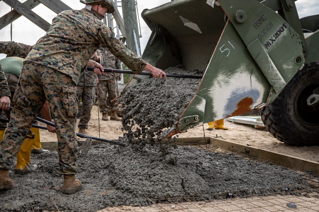 Combat engineers with Special Purpose Marine Air-Ground Task Force - Southern Command distribute concrete during a command post exercise at Marine Corps Base Camp Lejeune, North Carolina, April 10, 2020. The slab was created in order for the combat engineers to construct a short term building. The Marines and Sailors of SPMAGTF-SC use the training opportunity of the CPX to both show their capabilities in a controlled environment and prepare for the upcoming mission. SPMAGTF-SC is poised to conduct crisis response, theater security cooperation, and general engineering training alongside partner nation militaries in Latin America and the Caribbean. (U.S. Marine Corps photo by Cpl. Benjamin D. Larsen)