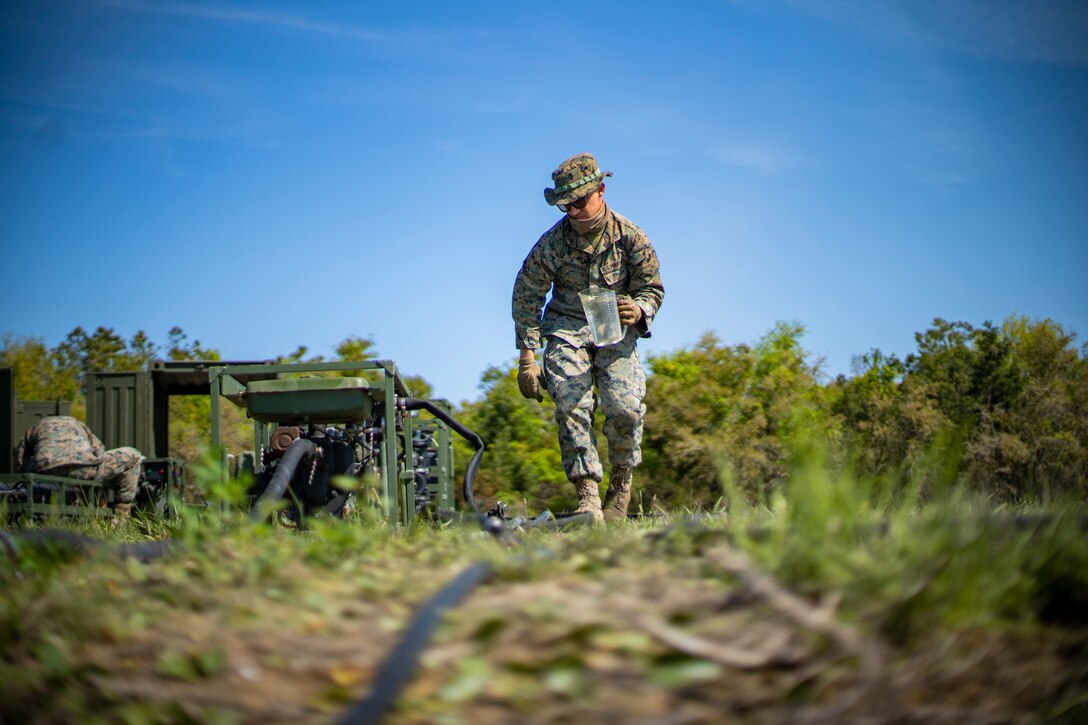 Lance Cpl. Daniel Bordenave, a water support technician with Special Purpose Marine Air-Ground Task Force - Southern Command, holds a cup of bay water ready to prime a water pump during ta command post exercise at Camp Lejeune, North Carolina, April 10, 2020. Water support technician Marines used lightweight water purification systems to purify water before providing it to the combat engineer Marines working at another site. The CPX increases readiness and challenges SPMAGTF-SC command and control, communications and timely decision-making capabilities through simulated real-world scenarios. SPMAGTF-SC will be deployed into the Southern Command area of operation to provide crisis response preparedness efforts, security cooperation training and engineering events to help strengthen relations with partner nations throughout Central and South America. Bordenave is from Pleasanton, California. (U.S. Marine Corps photo by Sgt. Andy O. Martinez)