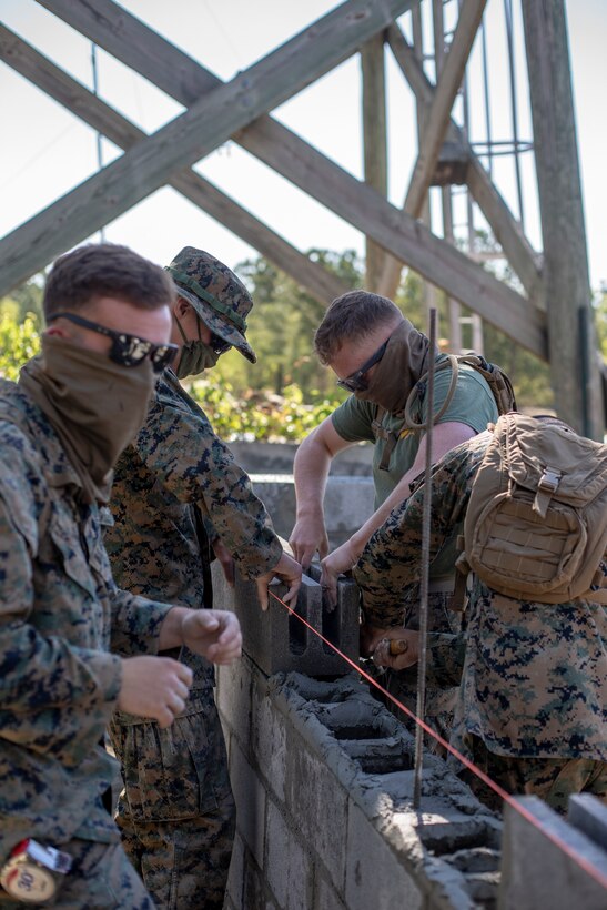 Engineers with Special Purpose Marine Air-Ground Task Force - Southern Command place and level cylinder blocks during a general exercise at Marine Corps Base Camp Lejeune, North Carolina, April 14, 2020. The engineers must ensure the cylinder blocks fit correctly to prevent problems from developing further along in the project. The GENEX includes training events such as engineering projects and evacuation control center training scenarios that will help build the SPMAGTF-SC for their final certification exercise. These training events also provide the Marines and Sailors with real-world scenarios to prepare them for their deployment to assist partner nation militaries in Latin America and the Caribbean. (U.S. Marine Corps photo by Cpl. Benjamin D. Larsen)