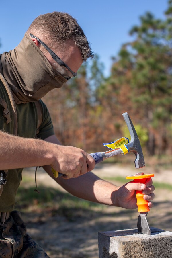 Cpl. Blake Thompson, a combat engineer with Special Purpose Marine Air-Ground Task Force - Southern Command, hammers out spaces in cylinder blocks during a general exercise at Marine Corps Base Camp Lejeune, North Carolina, April 14, 2020. Thompson was assuring that each block would fit together to keep structural integrity. The GENEX includes training events such as engineering projects and evacuation control center training scenarios that will help build the SPMAGTF-SC for their final certification exercise. These training events also provide the Marines and Sailors with real-world scenarios to prepare them for their deployment to assist partner nation militaries in Latin America and the Caribbean. Thompson is a native of Portland, Oregon. (U.S. Marine Corps photo by Cpl. Benjamin D. Larsen)