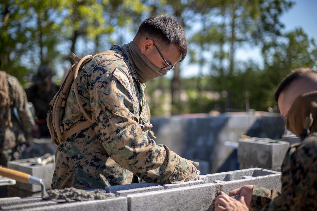 Lance Cpl. Tristan Pickens, a combat engineer with Special Purpose Marine Air-Ground Task Force - Southern Command, levels a cylinder block wall during a general exercise at Marine Corps Base Camp Lejeune, North Carolina, April 14, 2020. Pickens, alongside the other combat engineers, leveled the wall to help their construction project maintain its overall structural integrity. The GENEX includes training events such as engineering projects and evacuation control center training scenarios that will help build the SPMAGTF-SC for their final certification exercise. These training events also provide the Marines and Sailors with real-world scenarios to prepare them for their deployment to assist partner nation militaries in Latin America and the Caribbean. Pickens is a native of Jefferson, Oregon. (U.S. Marine Corps photo by Cpl. Benjamin D. Larsen)