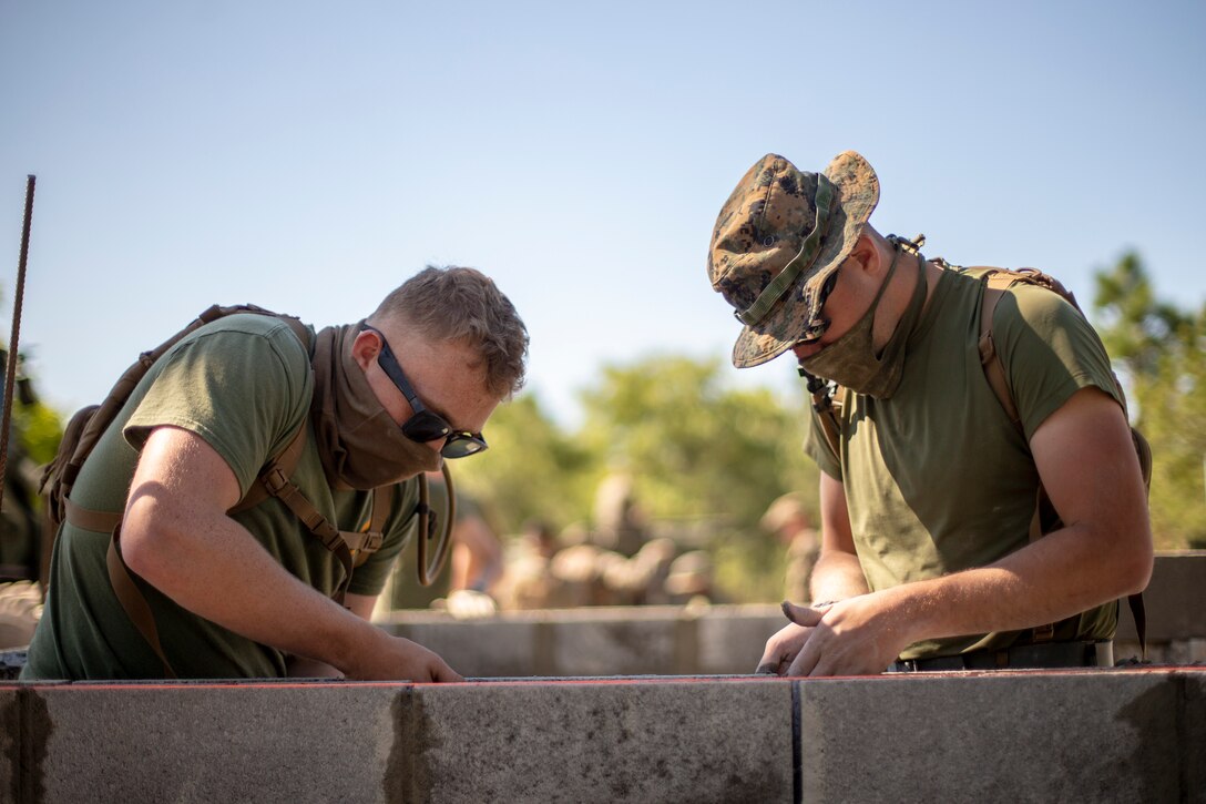 Lance Cpl. Mathew Dieter, left, and Cpl. Talon Malone, right, both combat engineers with Special Purpose Marine Air-Ground Task Force - Southern Command, level a cylinder block wall during a general exercise at Marine Corps Base Camp Lejeune, North Carolina, April 14, 2020. The combat engineers leveled the wall to help their construction project maintain its overall structural integrity. The GENEX includes training events such as engineering projects and evacuation control center training scenarios that will help build the SPMAGTF-SC for their final certification exercise. These training events also provide the Marines and Sailors with real-world scenarios to prepare them for their deployment to assist partner nation militaries in Latin America and the Caribbean. Dieter is a native of Portland, Oregon. Malone is a native of Estacada, Oregon. (U.S. Marine Corps photo by Cpl. Benjamin D. Larsen)
