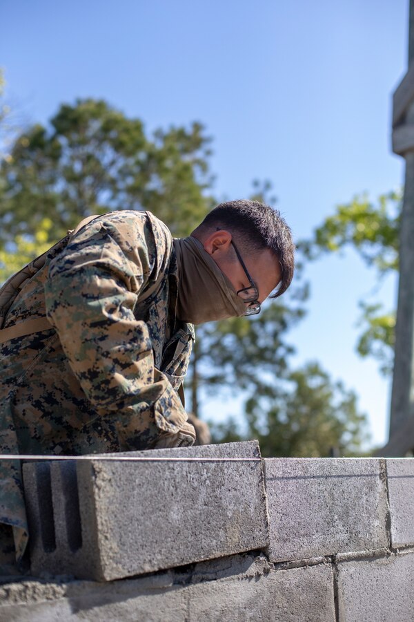 Lance Cpl. Tristan Pickens, a combat engineer with Special Purpose Marine Air-Ground Task Force - Southern Command, adds a cylinder block to the wall during a general exercise at Marine Corps Base Camp Lejeune, North Carolina, April 14, 2020. The engineers must ensure the cylinder blocks fit correctly to prevent problems from developing further along in the project. The GENEX includes training events such as engineering projects and evacuation control center training scenarios that will help build the SPMAGTF-SC for their final certification exercise. These training events also provide the Marines and Sailors with real-world scenarios to prepare them for their deployment to assist partner nation militaries in Latin America and the Caribbean. Pickens is a native of Jefferson, Oregon. (U.S. Marine Corps photo by Cpl. Benjamin D. Larsen)