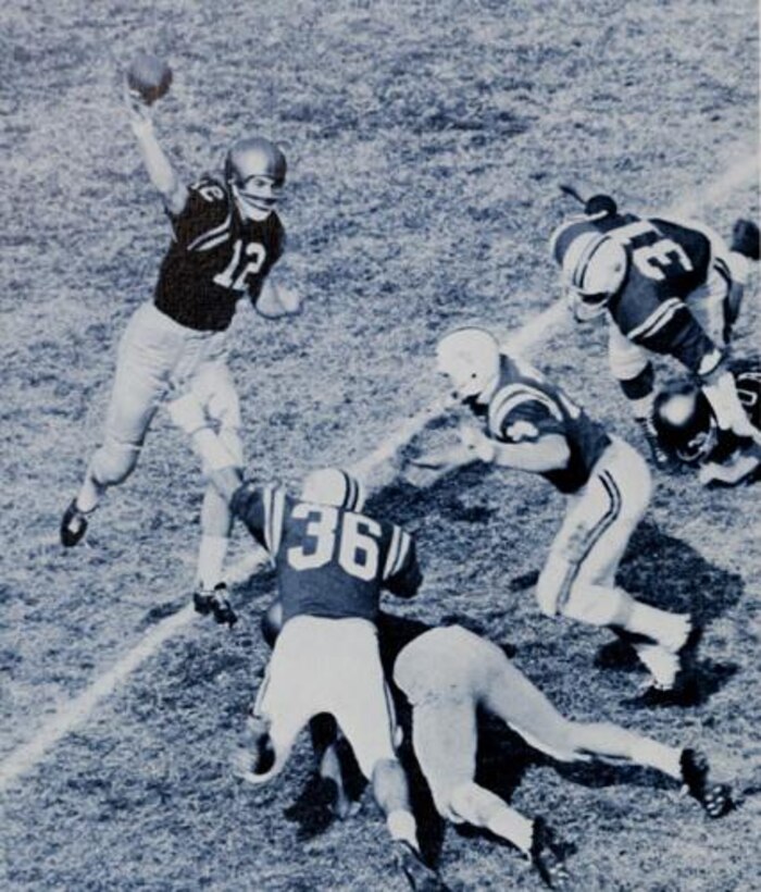 A quarterback prepares to throw the ball as the defensive line approaches.