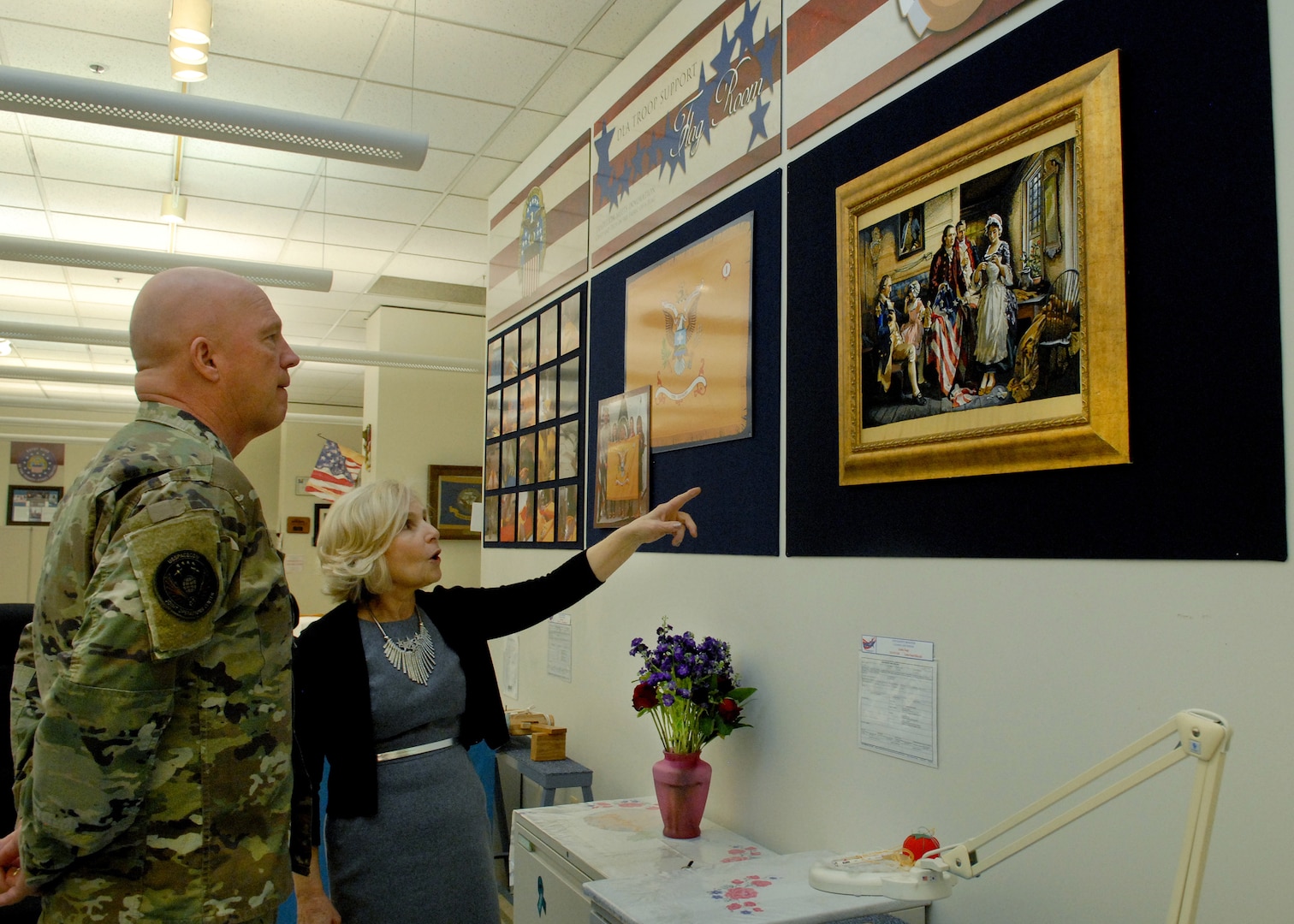 Flag room Supervisor Linda Farrell points to an embroidered flag depicting President George Washington and Betsy Ross with U.S. Space Force Commander Gen. John W. “Jay” Raymond