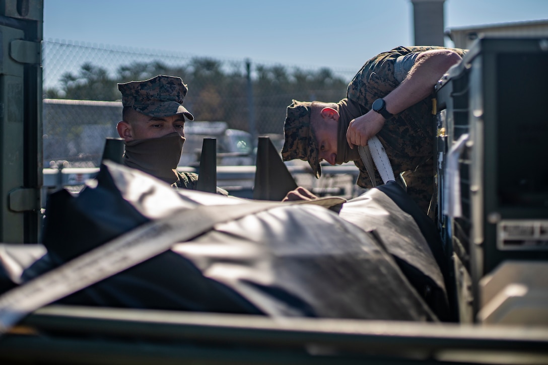 Cpl. Kyle Lang, a refrigeration and air conditioning technician with Special Purpose Marine Air-Ground Task Force - Southern Command, and Cpl. Gennadiy Tkachuk, right, an engineer equipment electrical systems technician with SPMAGTF-SC, tie down equipment during a general exercise at Camp Lejeune, North Carolina, April 14, 2020. The GENEX includes training events such as engineering projects and evacuation control center training scenarios that will help build the SPMAGTF-SC for their final certification exercise. These training events also provide the Marines and Sailors with real-world scenarios to prepare them for their deployment to assist partner nation militaries in Latin America and the Caribbean.  Lang is from Corvallis, Oregon. Tkachuk is a native of Hillsboro, Oregon. (U.S. Marine Corps photo by Sgt. Andy O. Martinez)