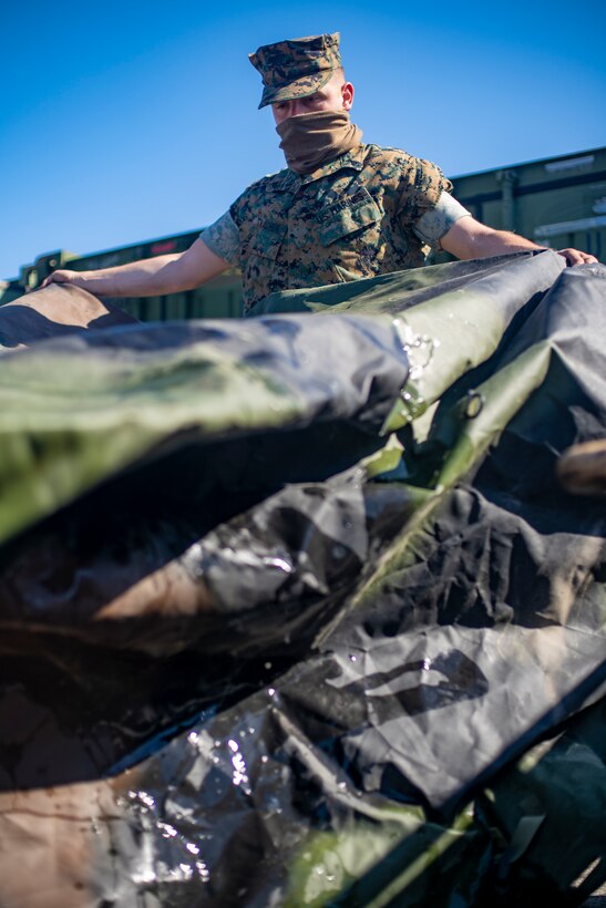Cpl. Gennadiy Tkachuk, an engineer equipment electrical systems technician with Special Purpose Marine Air-Ground Task Force - Southern Command, folds a tarp during a general exercise at Camp Lejeune, North Carolina, April 14, 2020. The GENEX includes training events such as engineering projects and evacuation control center training scenarios that will help build the SPMAGTF-SC for their final certification exercise. These training events also provide the Marines and Sailors with real-world scenarios to prepare them for their deployment to assist partner nation militaries in Latin America and the Caribbean. Tkachuk is a native of Hillsboro, Oregon. (U.S. Marine Corps photo by Sgt. Andy O. Martinez)