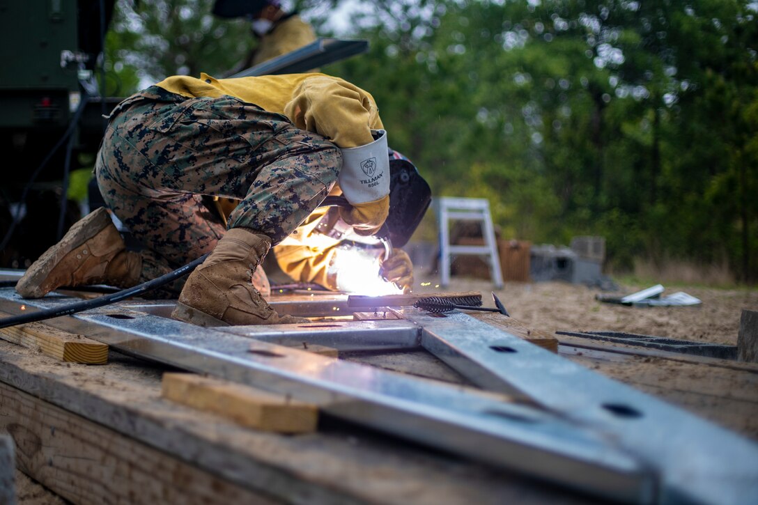Lance Cpl. Mason Sloan, a metal worker with Special Purpose Marine Air-Ground Task Force - Southern Command, tacks metal boards together during a general exercise at Camp Lejeune, North Carolina, April 15, 2020. The GENEX includes training events such as engineering projects and evacuation control center training scenarios that will help build the SPMAGTF-SC for their final certification exercise. These training events also provide the Marines and Sailors with real-world scenarios to prepare them for their deployment to assist partner nation militaries in Latin America and the Caribbean. Sloan is from Halsey, Oregon. (U.S. Marine Corps photo by Sgt. Andy O. Martinez)