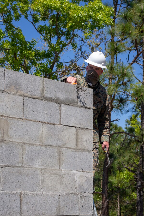 Lance Cpl. Vance Miller, a combat engineer with Special Purpose Marine Air-Ground Task Force - Southern Command, scrapes excess mortar from a cylinder block wall prior to the roof joints being placed during a general exercise at Marine Corps Base Camp Lejeune, North Carolina, April 16, 2020. Combat engineer Marines are increasing their construction skills in preparation for infrastructure improvement projects scheduled during their upcoming deployment to Latin America. The GENEX includes training events such as engineering projects and evacuation control center training scenarios that will help build the SPMAGTF-SC for their final certification exercise. These training events also provide the Marines and Sailors with real-world scenarios to prepare them for their deployment to assist partner nation militaries in Latin America and the Caribbean. Miller is a native of Salem, Oregon. (U.S. Marine Corps photo by Cpl. Benjamin D. Larsen)