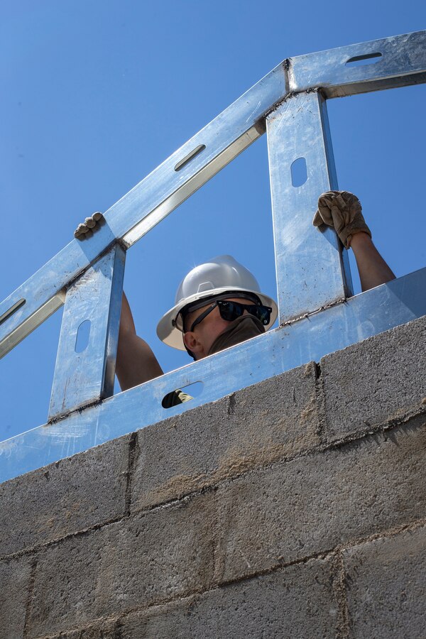 Cpl. Andrew McDonald, a combat engineer with Special Purpose Marine Air-Ground Task Force - Southern Command, holds steady a prefabricated roof joint during a general exercise at Marine Corps Base Camp Lejeune, North Carolina, April 16, 2020. Combat engineer Marines are increasing their construction skills in preparation for infrastructure improvement projects scheduled during their upcoming deployment to Latin America. The GENEX includes training events such as engineering projects and evacuation control center training scenarios that will help build the SPMAGTF-SC for their final certification exercise. These training events also provide the Marines and Sailors with real-world scenarios to prepare them for their deployment to assist partner nation militaries in Latin America and the Caribbean. McDonald is a native of Dallas, Oregon. (U.S. Marine Corps photo by Cpl. Benjamin D. Larsen)
