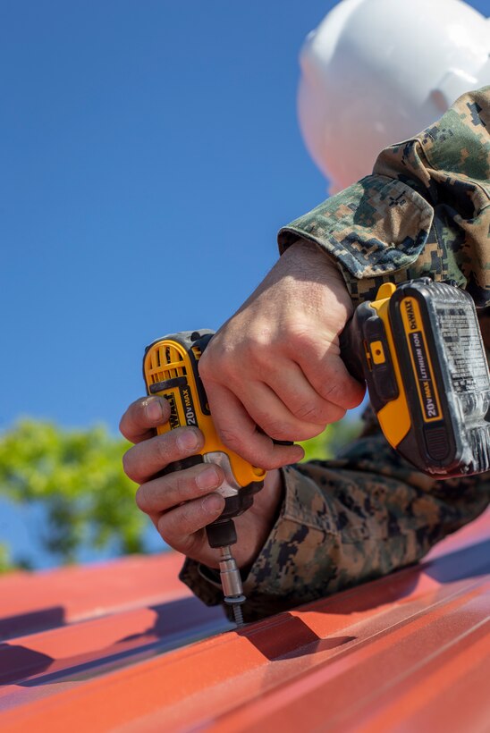 Lance Cpl. Cody Canada, a combat engineer with Special Purpose Marine Air-Ground Task Force - Southern Command, screws together roof panels for a newly constructed building during the general exercise at Marine Corps Base Camp Lejeune, North Carolina, April 17, 2020. The GENEX includes training events such as engineering projects and evacuation control center training scenarios that will help build the SPMAGTF-SC for their final certification exercise. These training events also provide the Marines and Sailors with real-world scenarios to prepare them for their deployment to assist partner nation militaries in Latin America and the Caribbean. Canada is a native of Tacoma, Washington. (U.S. Marine Corps photo by Cpl. Benjamin D. Larsen)