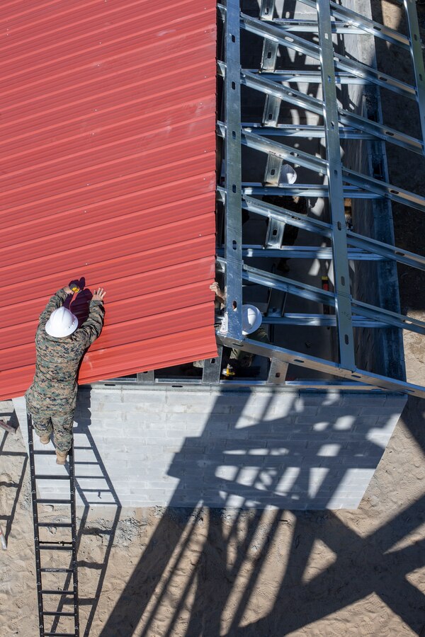 Lance Cpl. Cody Canada, a combat engineer with Special Purpose Marine Air-Ground Task Force - Southern Command, drills together roof panels atop a newly constructed building during a general exercise at Marine Corps Base Camp Lejeune, North Carolina, April 17, 2020. The GENEX includes training events such as engineering projects and evacuation control center training scenarios that will help build the SPMAGTF-SC for their final certification exercise. These training events also provide the Marines and Sailors with real-world scenarios to prepare them for their deployment to assist partner nation militaries in Latin America and the Caribbean. Canada is a native of Tacoma, Washington. (U.S. Marine Corps photo by Cpl. Benjamin D. Larsen)