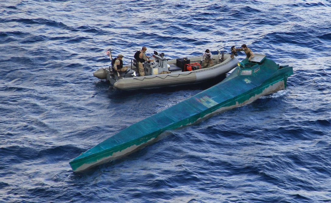 A Coast Guard boarding team in a boat approach a low profile semi-submersible.