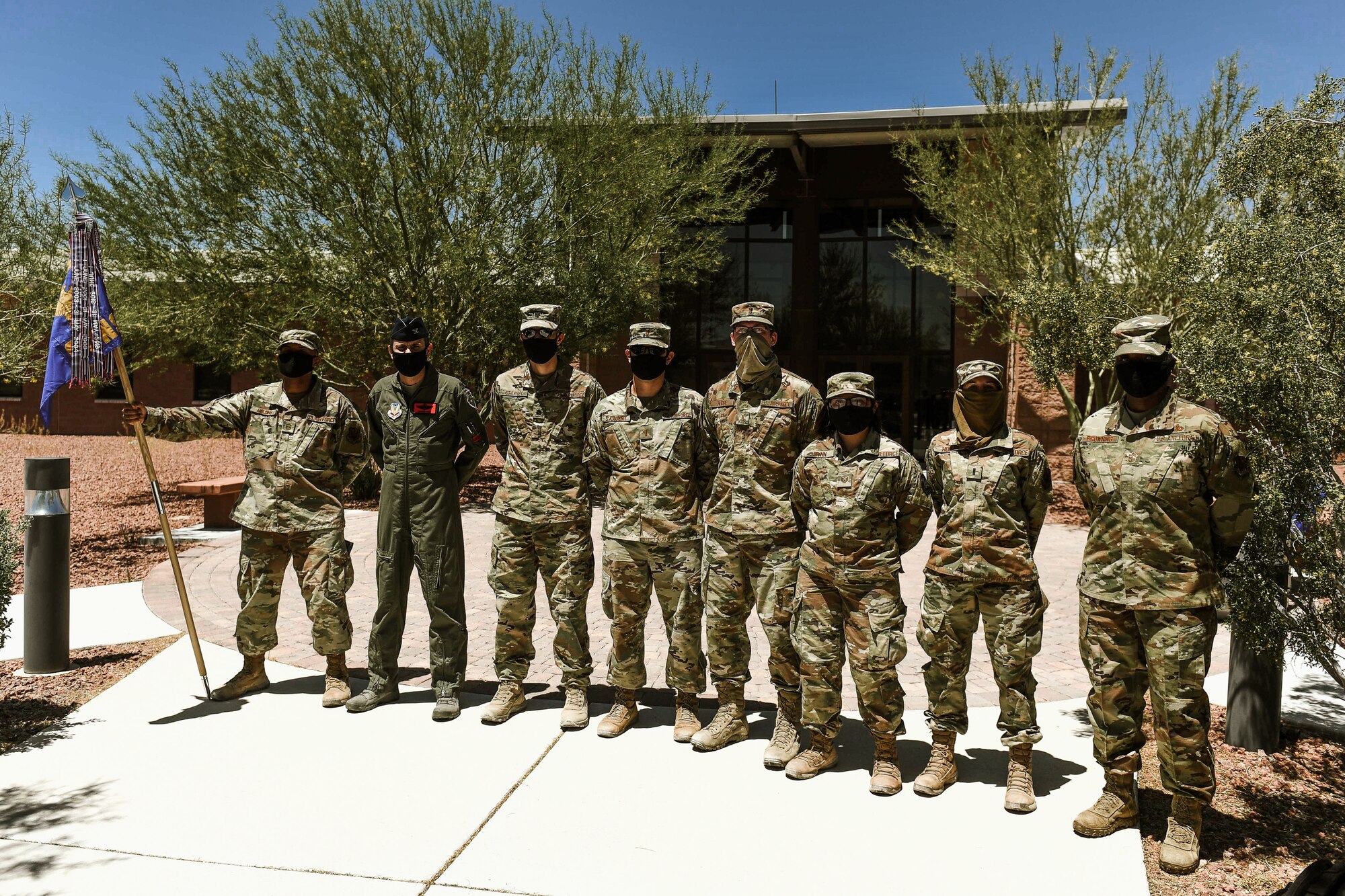 Airmen from the 99th Contracting Squadron dressed in OCPs and wearing facemasks stand alongside Col. James Price, 432nd Wing/432nd Air Expeditionary Wing vice commander and Chief Master Sgt. Michelle Browning, 432nd WG/AEW command chief, as they pose for a group photo.