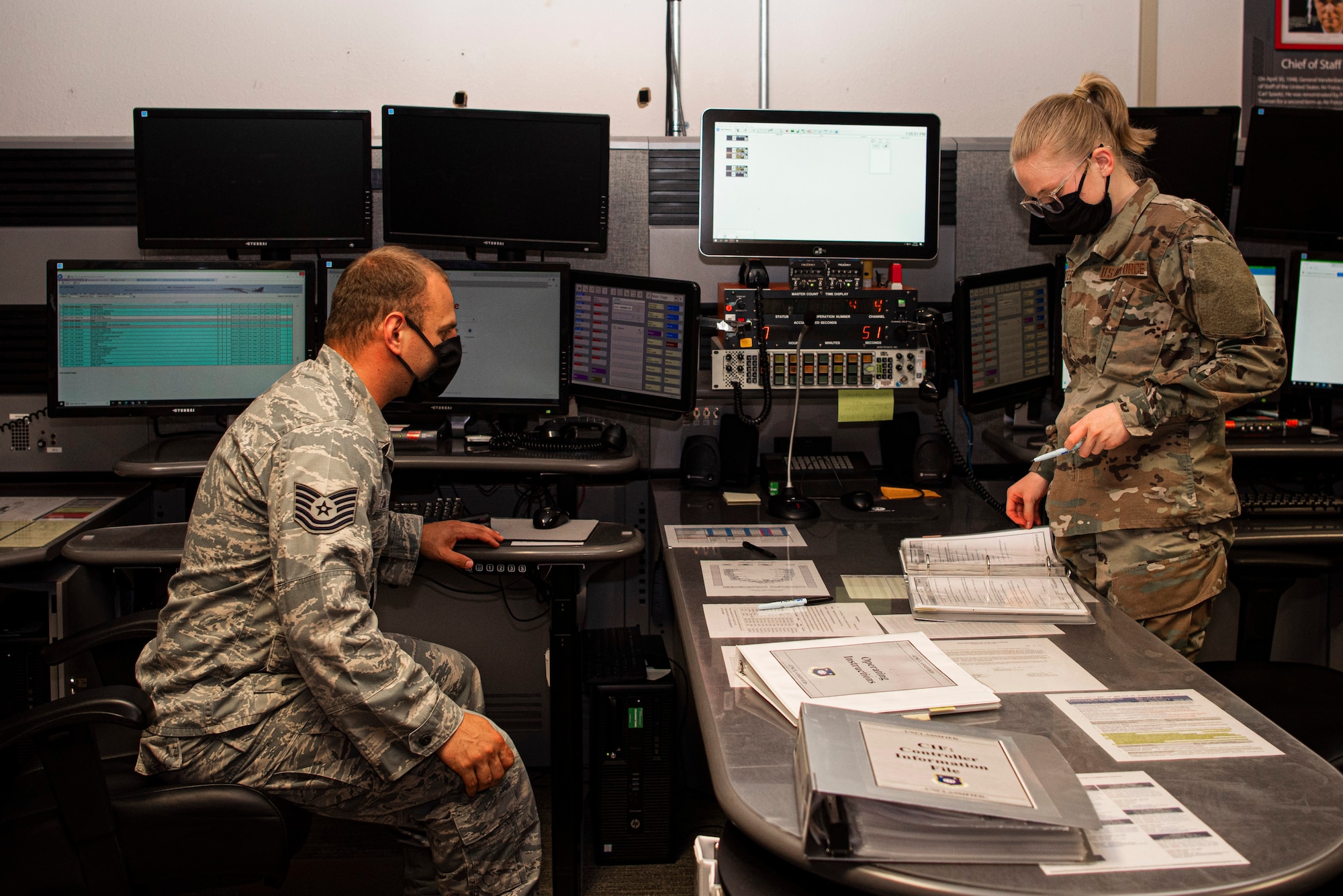 Tech. Sgt Gregory Forte, 30th Space Wing senior emergency actions controller, works on a checklist with Airman Basic Julia Hitter, 30th Space Wing junior emergency actions controller May 18, 2020, at Vandenberg Air Force Base, Calif. Due to COVID-19, the 30th SW Command Post team broke into three shifts, with 2 controllers per shift. To ensure each shift and controller team had the same information, the team developed a shift change over, continuity binder and a shift checklist. (U.S. Air Force photo by Senior Airman Hanah Abercrombie)