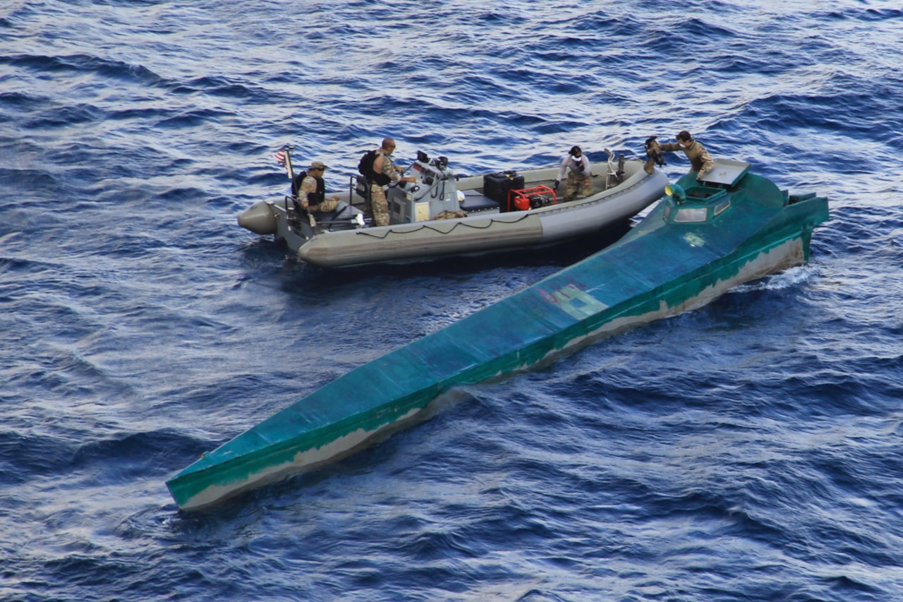 U.S. service members on an inflatable boat alongside a drug-running vessel.