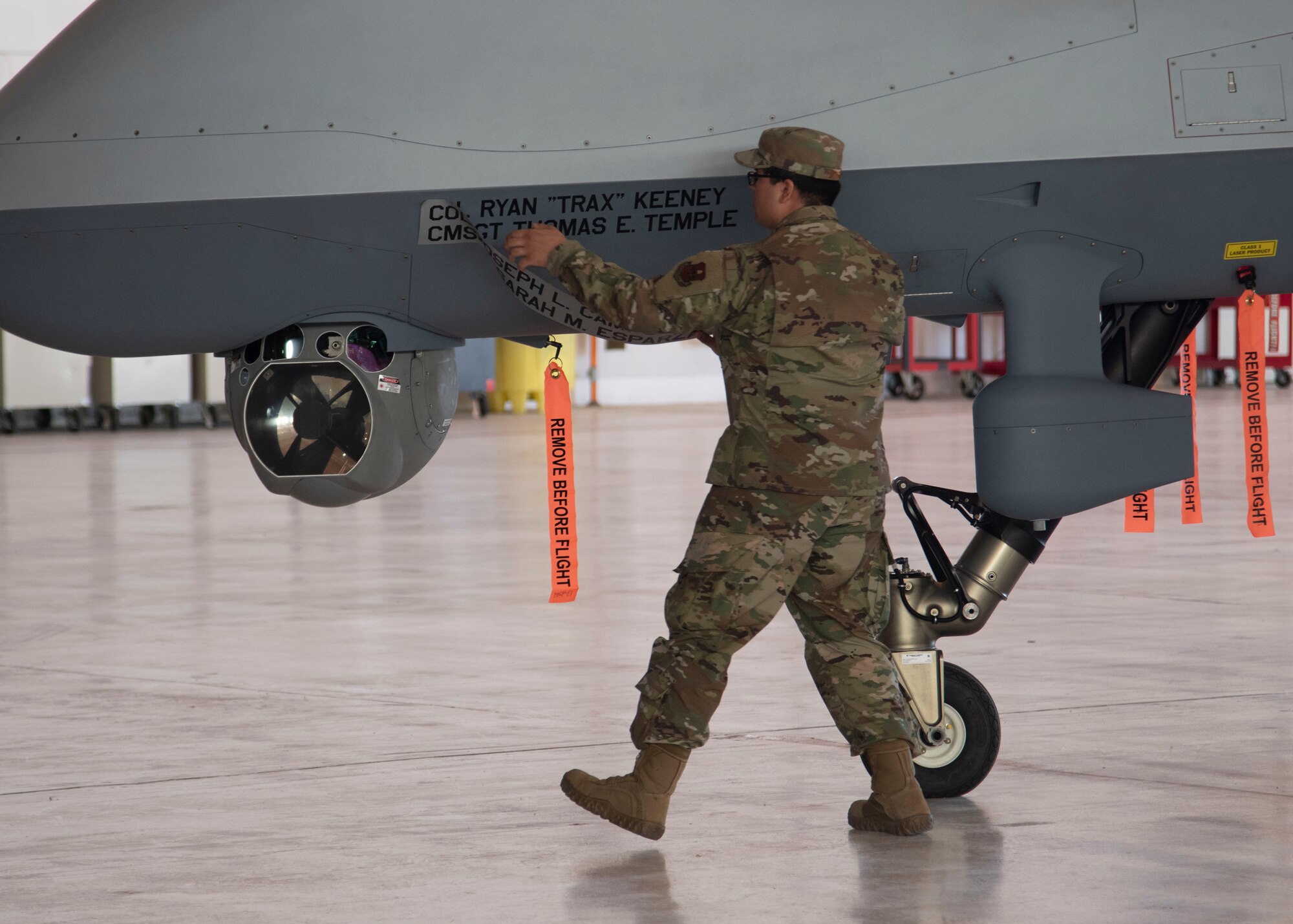 Senior Airman Jorge Garcia, 49th Aircraft Maintenance Squadron assistant dedicated crew chief, unveils Col. Ryan Keeney, 49th Wing commander, and Chief Master Sgt. Thomas Temple’s, 49th WG command chief, name on an MQ-9 Reaper, during the 49th WG Change of Command ceremony, May 21, 2020, on Holloman Air Force Base, N.M. Holloman is the premiere training base for F-16 Fighting Falcon and MQ-9 pilots and sensor operators. (U.S. Air Force photo by Tech. Sgt. BreeAnn Sachs)