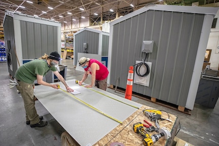 Peyton Gingrey, left, and James Zeitler, both composite plastic fabricators with Shop 64, assemble new hand washing stations May 19, 2020 inside Shop 64 Woodcrafters at Puget Sound Naval Shipyard & Intermediate Maintenance Facility in Bremerton, Washington.