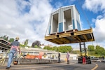 Shop 740 crew members lift a new hand washing station into Dry Dock 4 May 19, 2020 at Puget Sound Naval Shipyard & Intermediate Maintenance Facility in Bremerton, Washington.