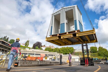 Shop 740 crew members lift a new hand washing station into Dry Dock 4 May 19, 2020 at Puget Sound Naval Shipyard & Intermediate Maintenance Facility in Bremerton, Washington.