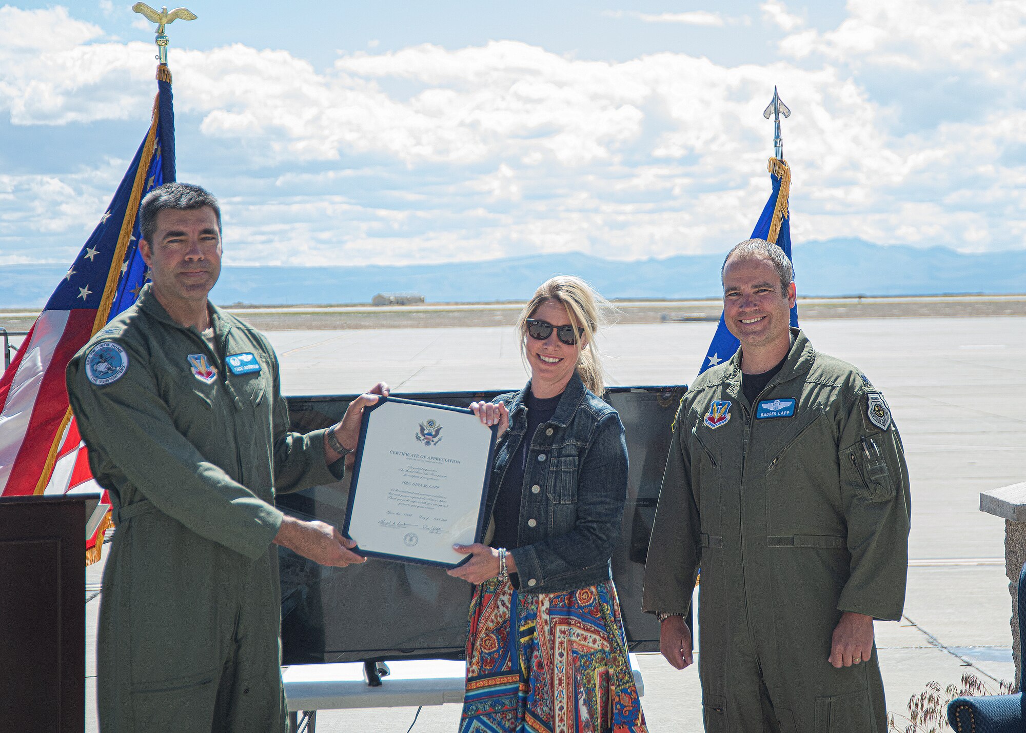 U.S. Air Force Col. Richard A. Goodman, 366th Fighter Wing commander, (left) gives Gina Lapp, wife of Lt. Col. Aaron C. “Badger” Lapp, (mid) a certificate of appreciation, May 15, 2020, on Mountain Home Air Force Base, Idaho. Lapp has been involved in significant deployments such as Operation INHERENT RESOLVE and Operation DELIBERATE RESOLVE. (U.S. Air Force photo by Airman 1st Class Akeem K. Campbell)