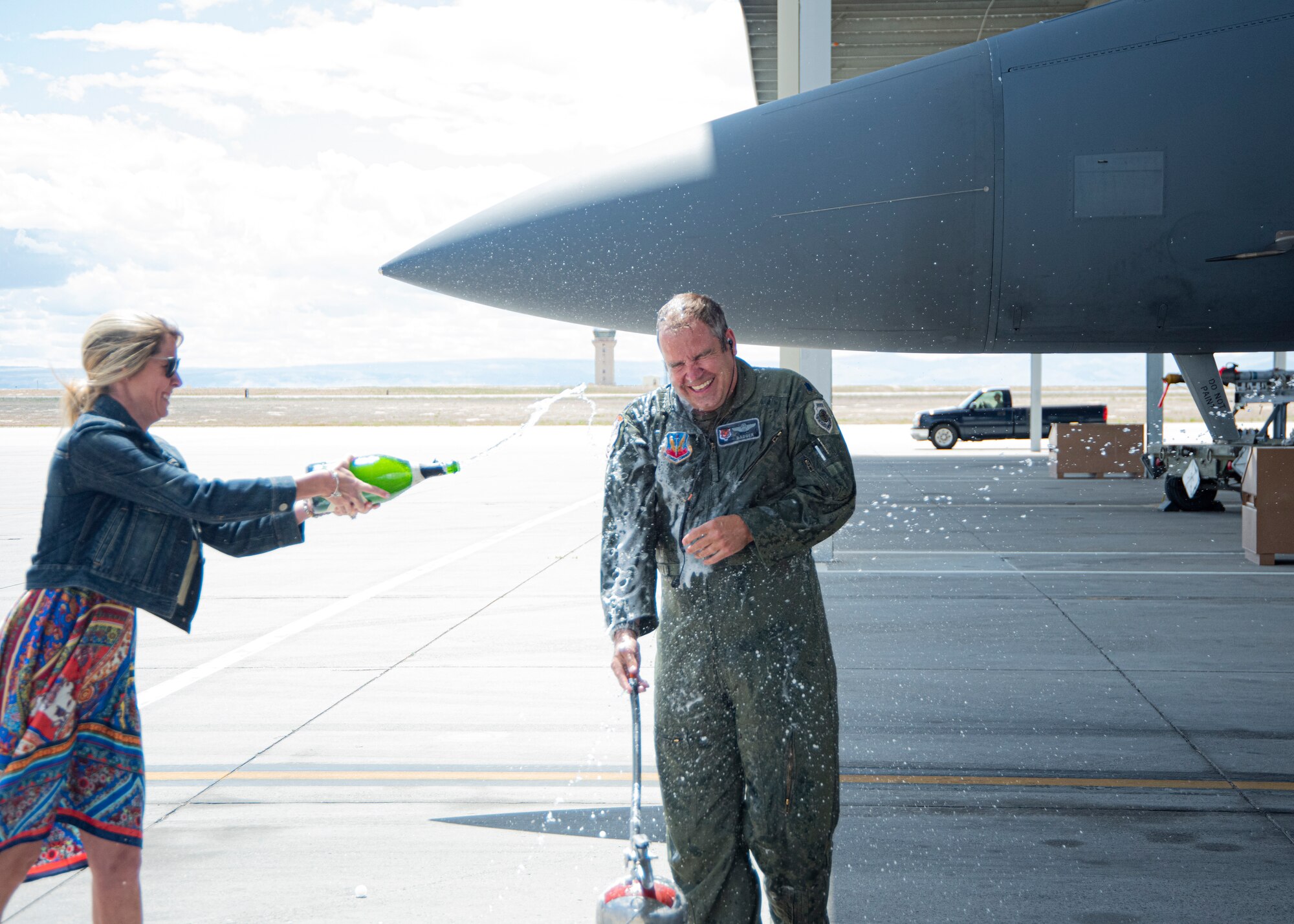 U.S. Air Force Lt. Col. Aaron C. “Badger” Lapp, 366th Fighter Wing director of operations and plans, gets sprayed with champagne by his wife, Gina Lapp, after completing his Fini Flight, May 15, 2020, on Mountain Home Air Force Base, Idaho. Getting sprayed with champagne by friends and family is part of the Fini Flight tradition. (U.S. Air Force photo by Airman 1st Class Akeem K. Campbell)