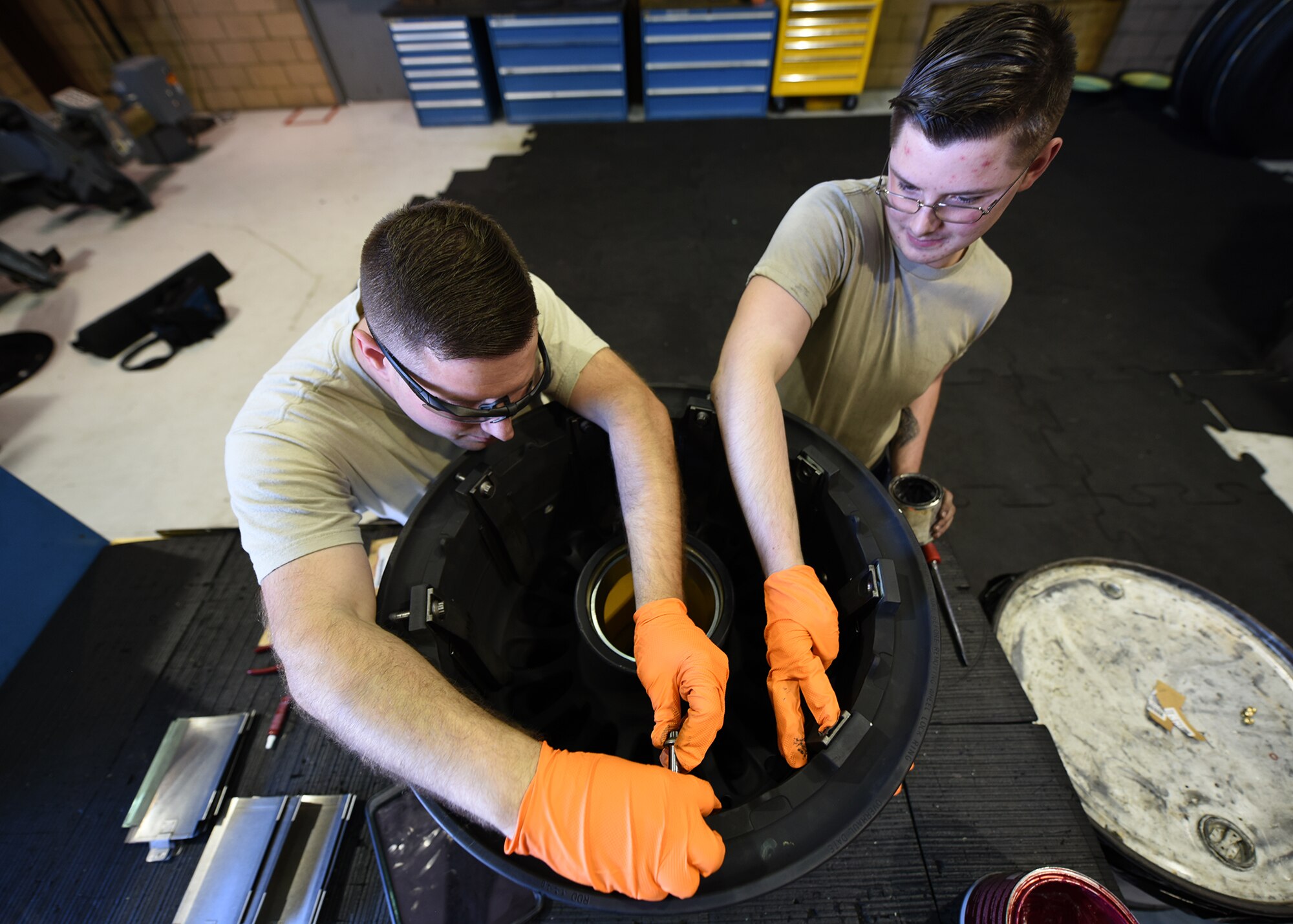 A photo of two Airmen working on a tire.
