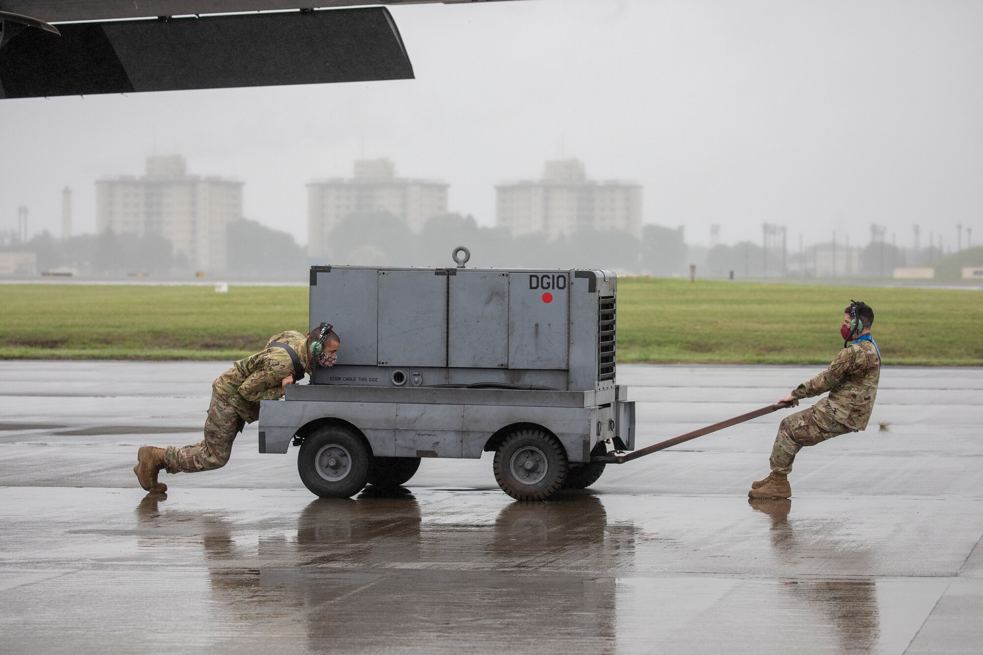 Crew chiefs assigned to the 374th Aircraft Maintenance Squadron push an A/M32 diesel generator into position prior to starting a C-130J Super Hercules during the Samurai Surge training exercise at Yokota Air Base, Japan, May 21, 2020.