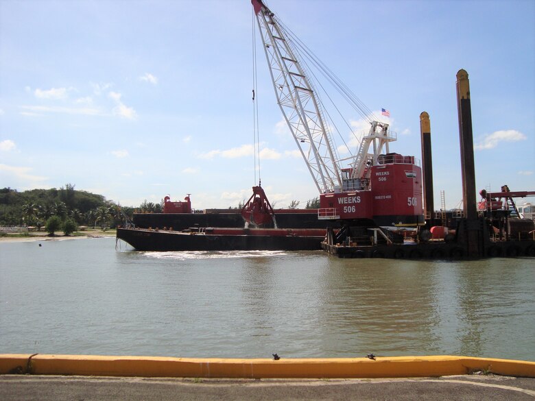 a red dredge with the claw lifted off the water