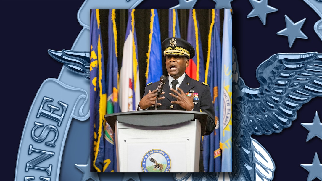 Army Lt. Gen. Darrell K. Williams delivers a keynote address from behind a lectern with flags in the background.