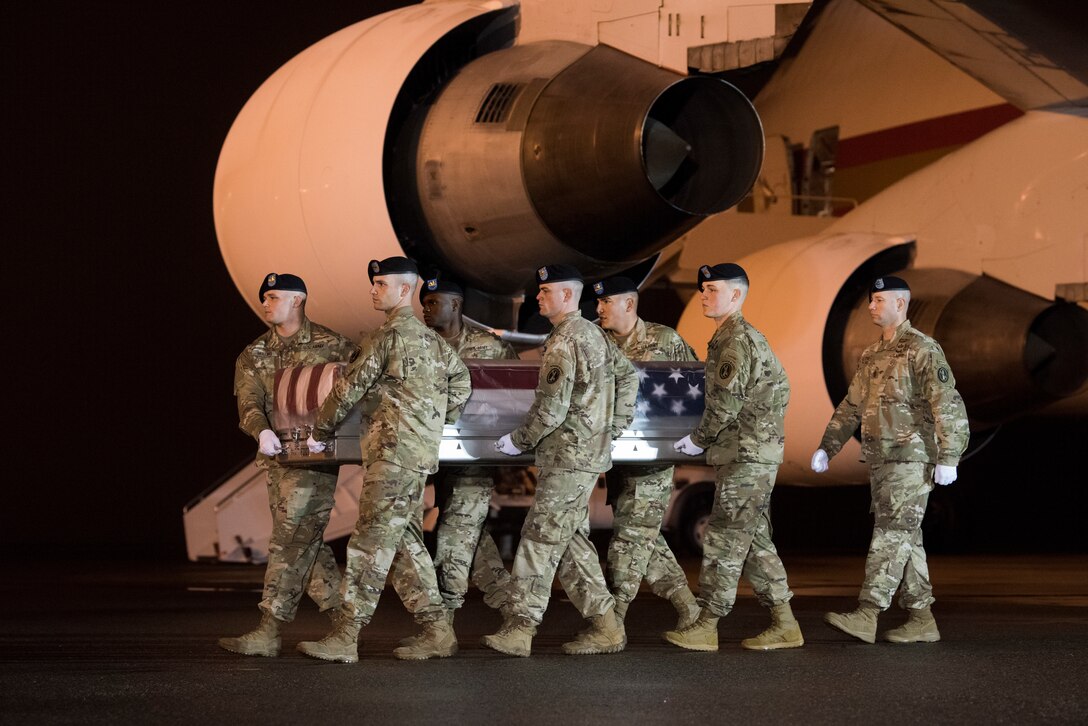 Soldiers carry casket off aircraft.