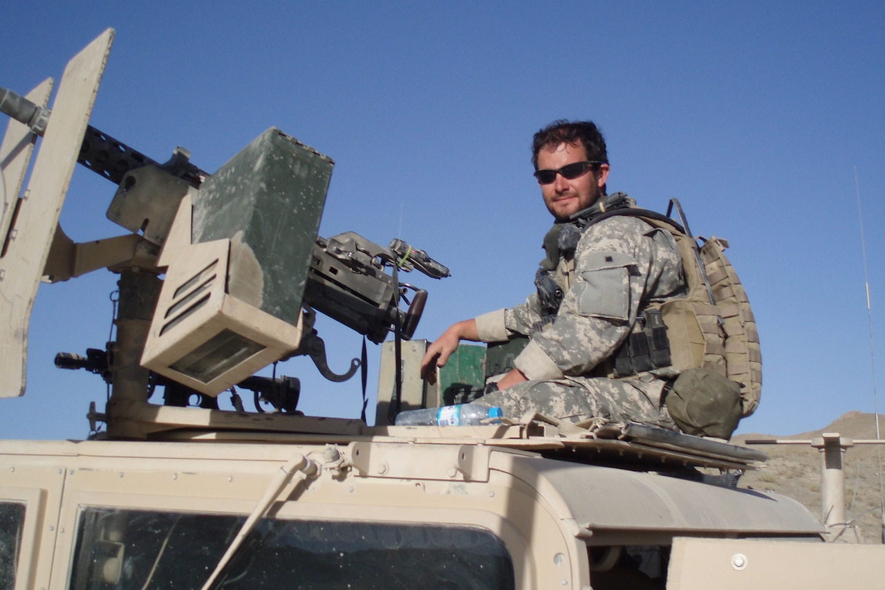 A soldier sits behind a gun mounted to a Humvee.