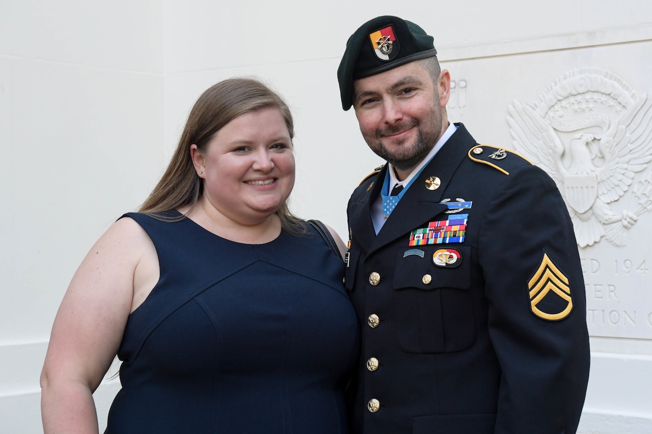A woman and a man in uniform pose for a photo.