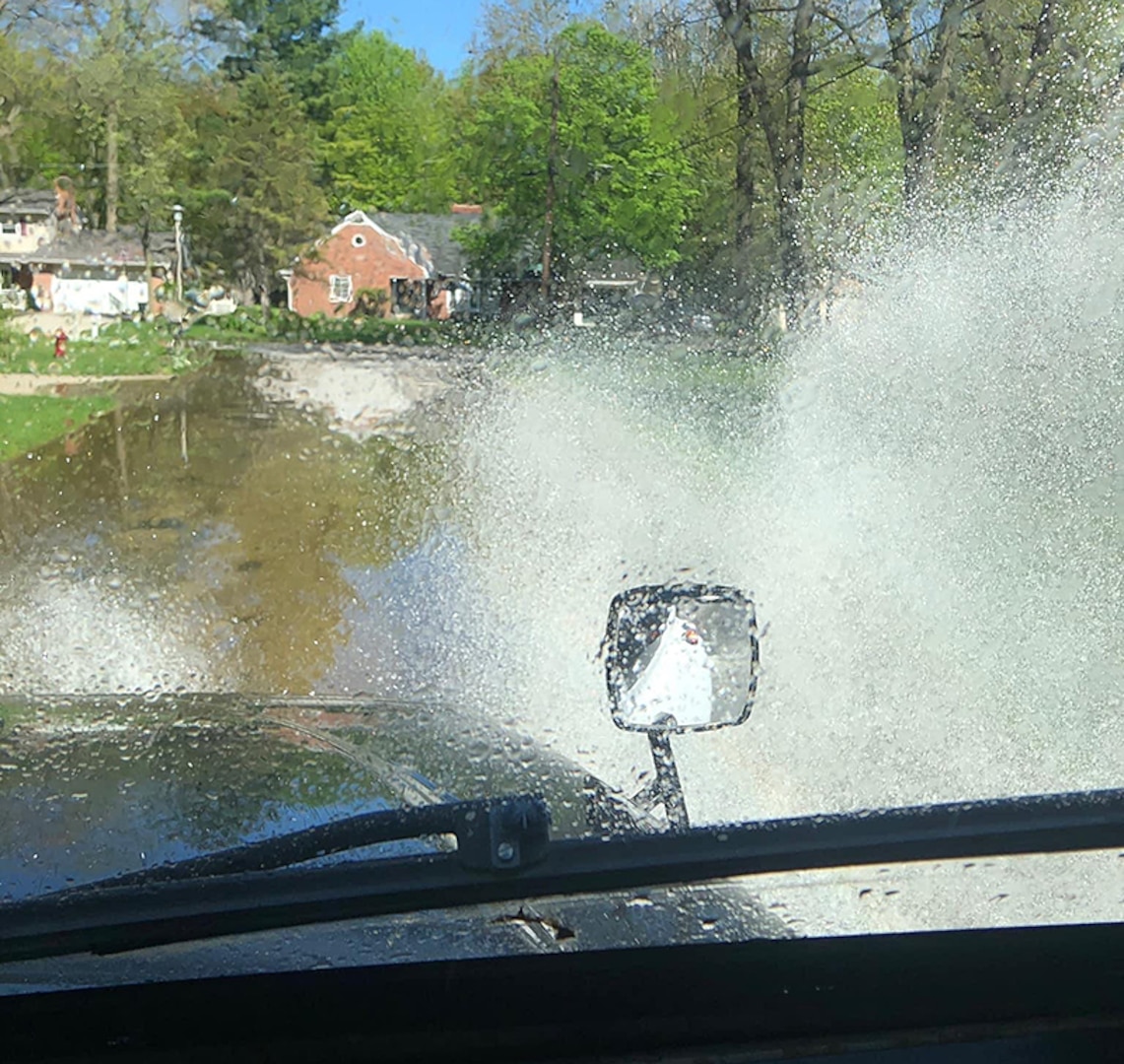 A tall military truck fords floodwaters.