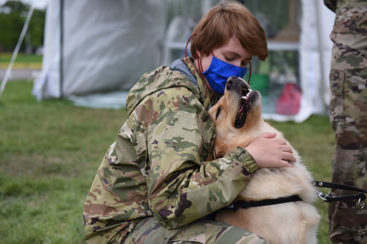An airman hugs a dog.