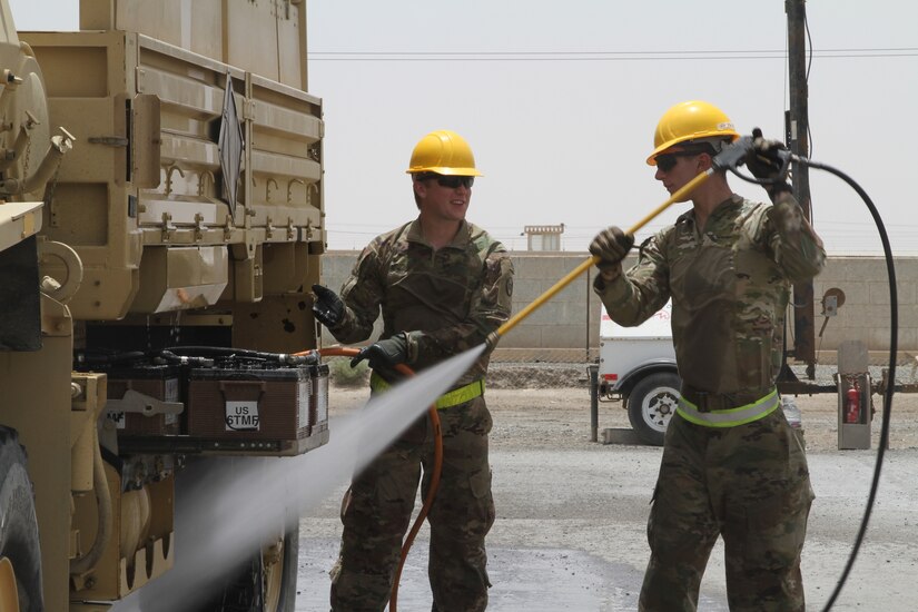U.S. Army Spc. Logan Drye and Pfc. Jordan schuh, assigned to the 30th Armored Brigade Combat Team, clean vehicles in Kuwait, May 13, 2020. The vehicles being prepared to be sent back to the U.S. After thorough cleaning and clearing by U.S. Customs officials. (U.S. Army photo by Sgt. Andrew Valenza)