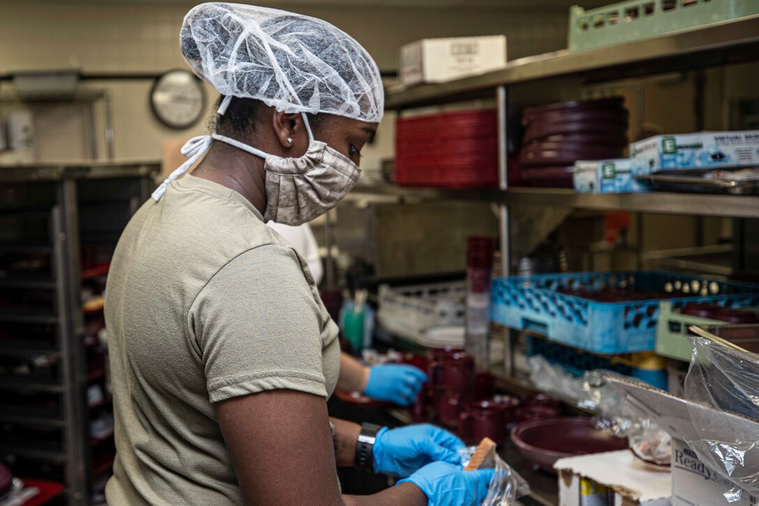 An airman in protective gear prepares food.