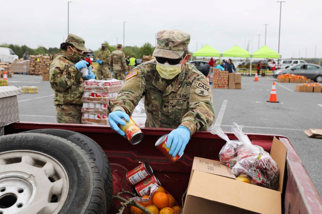 A soldier drops canned goods into a vehicle.