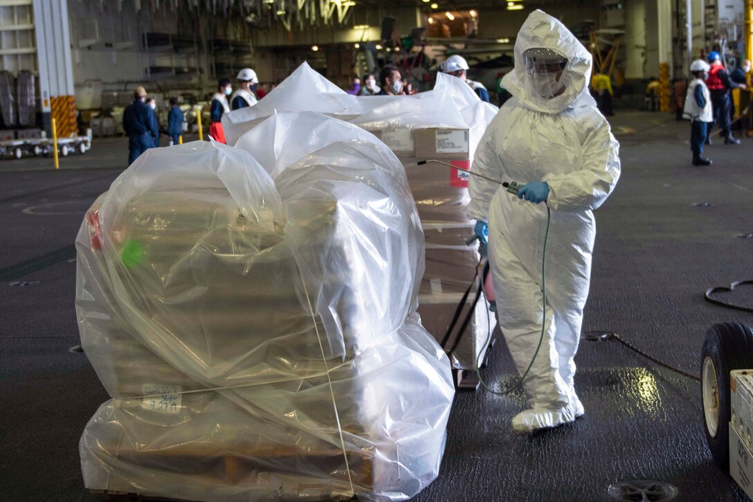 A sailor in protective gear cleans cargo.