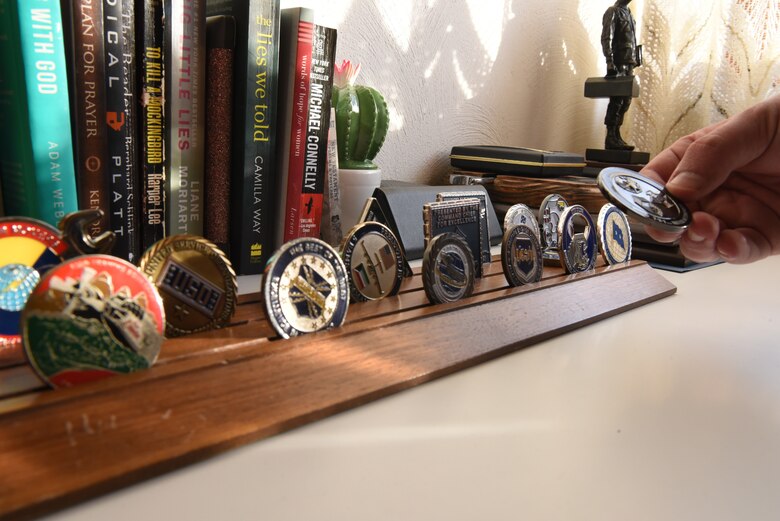 U.S. Air Force Staff Sgt. Taylor J. Eide, 721st Aircraft Maintenance Squadron quality assurance inspector, holds one of his many coins from the display at his home in Hütschenhausen, Germany, May 20, 2020.