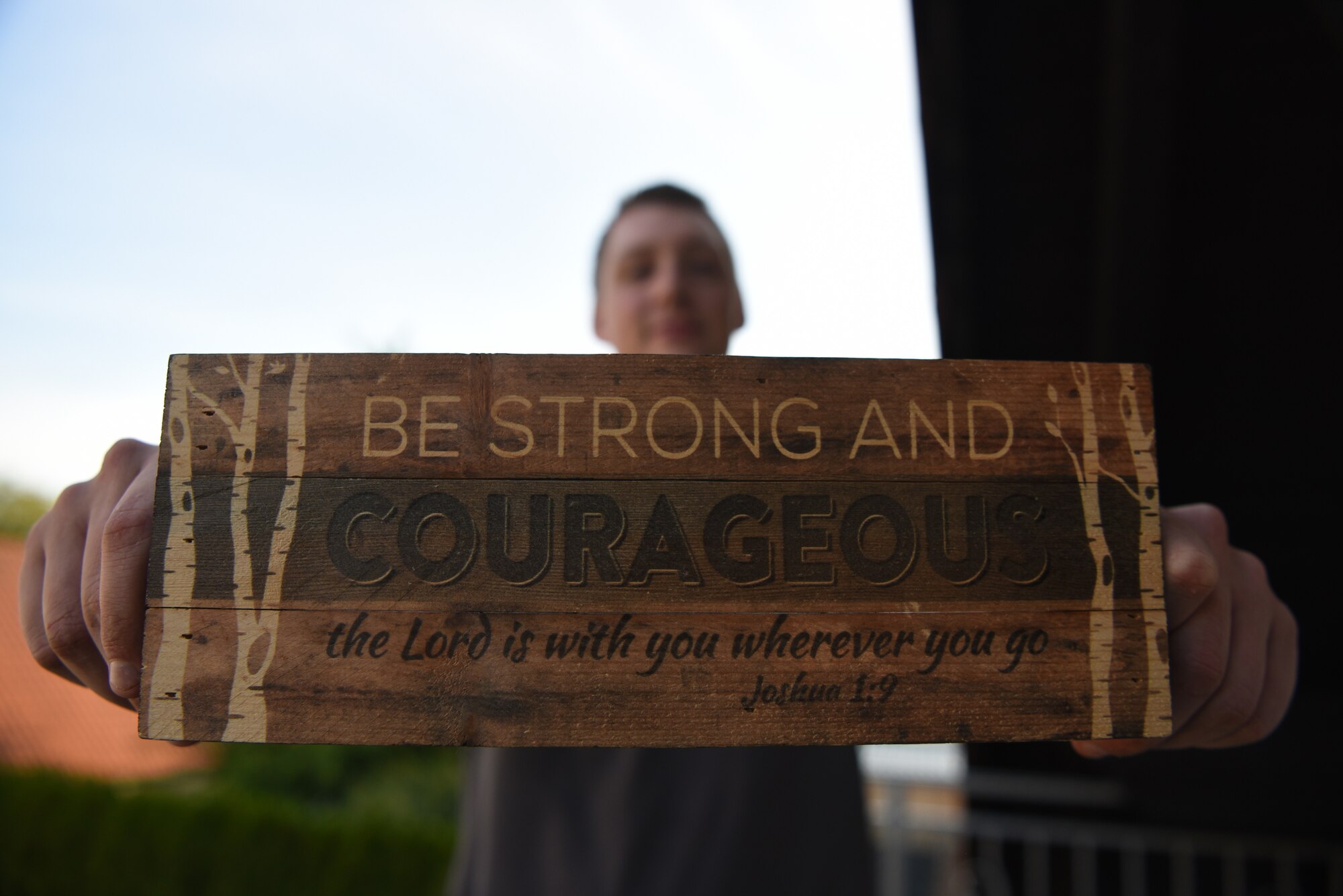 U.S. Air Force Staff Sgt. Taylor J. Eide, 721st Aircraft Maintenance Squadron quality assurance inspector, holds a sign given to him by his aunt at his home in Hütschenhausen, Germany, May 20, 2020.