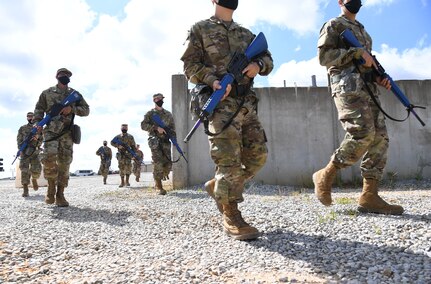Airmen in formation march with rifles