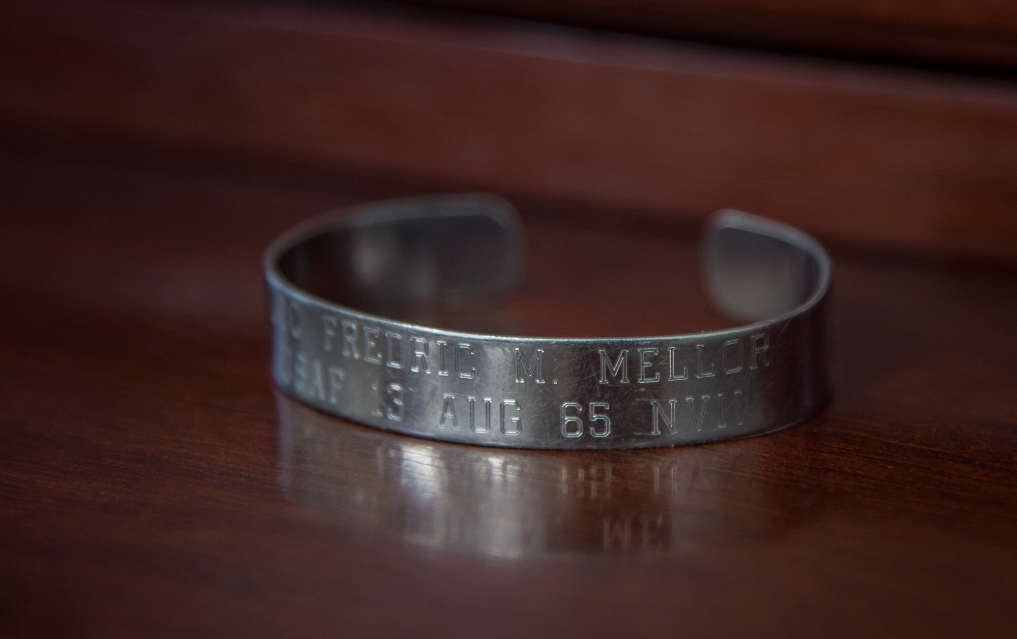 A memorial bracelet engraved with a name, Lt. Col. Fredric M. Mellor, and the date he went missing, rests on a table May 20, 2020 at McConnell Air Force Base, Kansas. Col. Mark Baran, 22nd Air Refueling Wing vice commander, has worn the bracelet for 18 years to honor the F-101 Voodoo pilot who was shot down on mission during the Vietnam War. (U.S. Air Force photo by Senior Airman Michaela Slanchik)